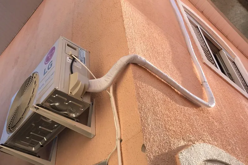 Condensadora na quina de uma casa, com tubulação acompanhando a parede